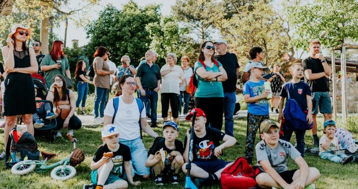 A diverse group of people enjoying a sunny day at an outdoor community event in a park setting.