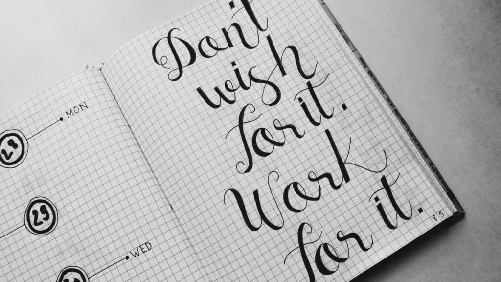 Close-up of motivational calligraphy on grid paper, inspiring message for productivity.