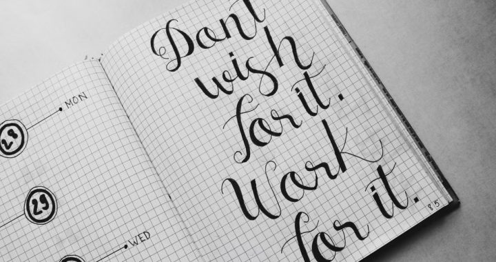 Close-up of motivational calligraphy on grid paper, inspiring message for productivity.